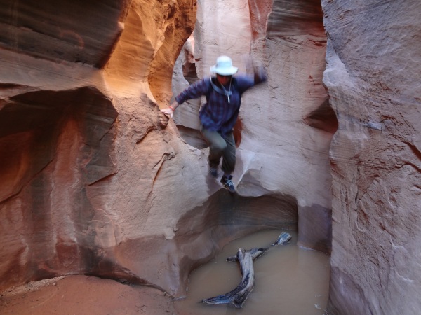 hiker jumps in peek-a-boo gulch slot canyon